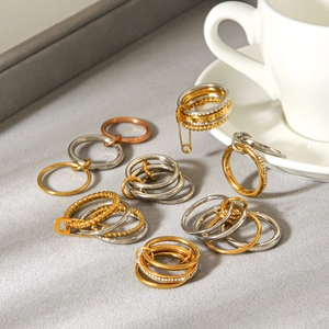 Multi-tone stainless steel ring set with safety pin design on gray velvet background