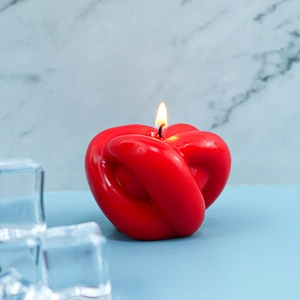 Gros plan d'une bougie parfumée rouge en forme de nœud avec une silhouette de cœur