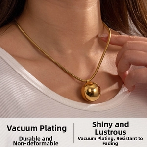Detailed view of a gold snake chain necklace with a mirror finish spherical pendant
