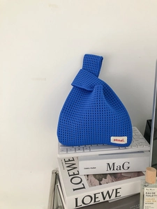 Close-up of electric blue knit handbag showing grid texture and red Hilldi brand tag