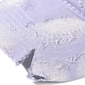 Detail view of frayed edges and distressed texture on a purple denim baseball cap