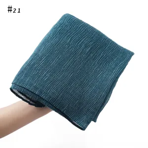 Detailed texture of dark green pleated cotton linen scarf with vertical accordion folds