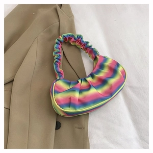 Detailed view of rainbow pleated shoulder bag on a beige blazer stylish background
