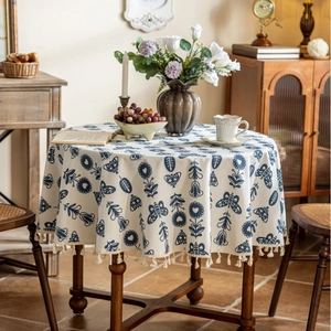 Detail of round cotton linen tablecloth with blue floral patterns and tassel edges