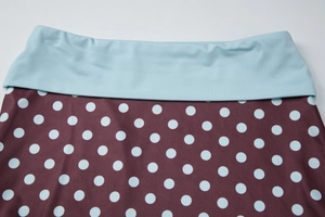 Détail de la taille haute bleue et du tissu bordeaux à pois bleu clair du vêtement