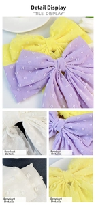 Close-up detail of oversized chiffon bow hair clips with textured polka dots in purple and yellow