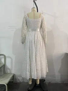 Détail de la texture en dentelle blanche et de la ceinture en satin sur robe longue
