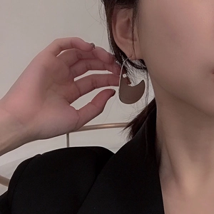 Minimalist C-shaped geometric hoop earrings in polished gold metal worn by a model