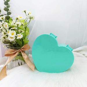 Joyero de plástico con forma de corazón verde menta sobre piel blanca con flores