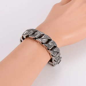 Vintage stainless steel wide Cuban chain bracelet with intricate floral engravings on model