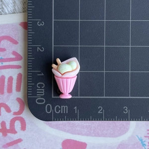 Miniature resin ice cream sundae charm with pink cup and green scoop shown with ruler for scale