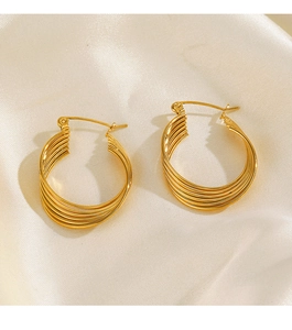 Detailed close-up of gold layered hoop earrings on soft beige silk background