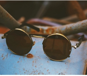 Steampunk round sunglasses detail with brass metal frame on industrial background