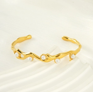 Dettaglio di un bracciale rigido vintage placcato oro 18k con eleganti perle bianche