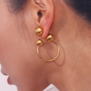 Detail view of gold stainless steel earrings with geometric triple ball and hoop design