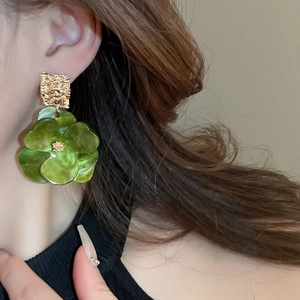 Gros plan d'une boucle d'oreille fleur en acrylique vert avec métal doré martelé sur mannequin