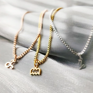 Detail view of gold, silver, and rose gold stainless steel zodiac pendants on box chains.