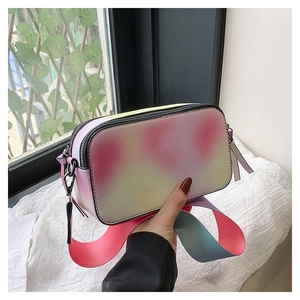 Detailed close-up of a tie-dye gradient camera bag with dual zippers and wide strap