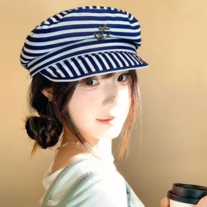Detail of blue and white striped sailor hat with metal anchor on female model