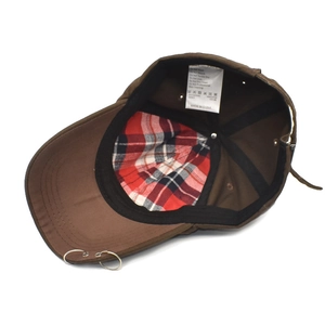Detail of dark brown cotton baseball cap showing silver metal rings and plaid lining