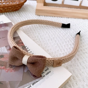 Detail of knitted bow headband with deep brown wool bow and cute leather rabbit patch