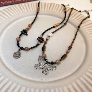 Bohemian handmade beaded necklaces with silver butterfly and coin pendants on tray