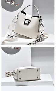 Detailed view of white leather bucket bag with wide patterned strap and metal bottom studs