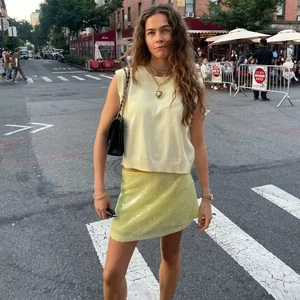 Tenue street chic avec débardeur en maille jaune et mini-jupe à paillettes assortie