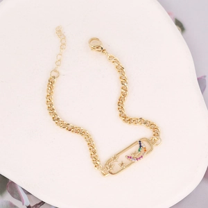 Detail of gold chain bracelet with star and rainbow zircon moon charm on white tray