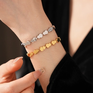 Detail of stacked gold and silver heart bracelets with hammered and polished finishes