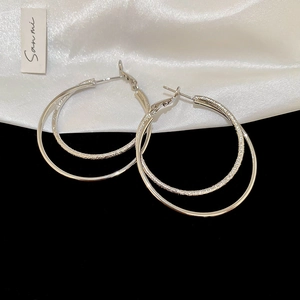 Macro detail of silver double hoop earrings with mirror finish and frosted texture layers