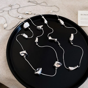 Close-up of irregular silver geometric beads on a long metallic y2k style necklace
