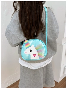 Girl wearing a blue unicorn crossbody bag with rainbow horn and heart embroidery detail