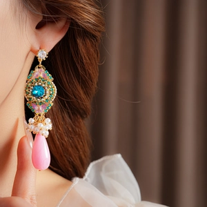 Détail de boucle d'oreille vintage dorée avec émail bleu et gemme rose en goutte