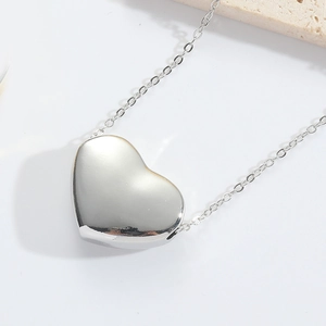 Detailed view of a silver minimalist heart pendant with a fine link chain necklace