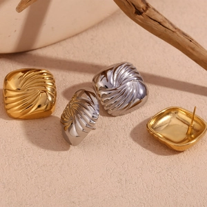 Macro shot of square gold and silver earrings with radial 3D wavy texture