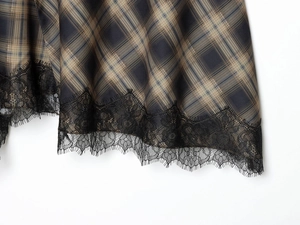 Détail de l'ourlet de jupe à carreaux avec bordure en dentelle noire et tissu tissé