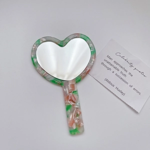 Close-up of heart-shaped acetate makeup mirror with pink and green marble patterns