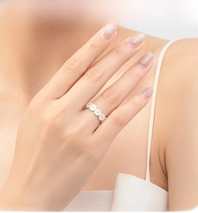 Detail of S925 sterling silver ring with white daisy enamel pattern on model's finger