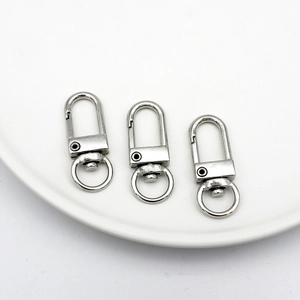 Detailed view of three silver swivel snap hooks with round keyrings on a white plate