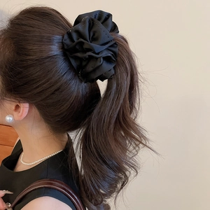Détail d'un grand chouchou en satin noir orné de strass brillants pour queue de cheval