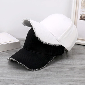 Detail of black and white teddy fleece baseball caps with rhinestone edges on wooden surface
