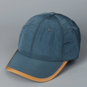 Vue détaillée du tissu en nylon froissé sarcelle foncé et bord en cuir marron de la casquette