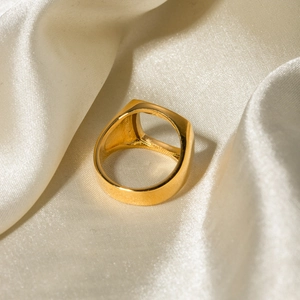 Close-up of golden square hollow ring with crystal on soft beige silk fabric