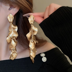 Close-up of matte gold long petal tassel earrings worn by a model in a side view