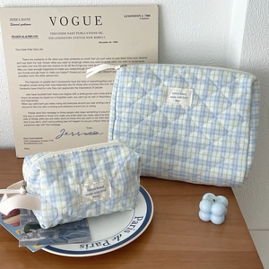 Detail of two-piece quilted plaid cosmetic bags in blue-green with fabric logo labels