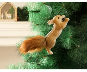 Close-up of fluffy squirrel ornament with pinecone hanging on a green Christmas tree
