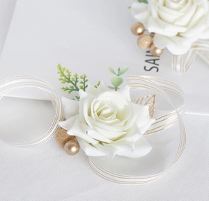 Detailed view of white artificial rose boutonniere with golden leaves and ribbon
