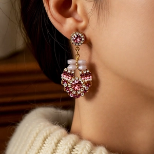 Detail view of a vintage silver needle drop earring with purple crystals on a model