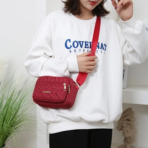 Red quilted nylon crossbody bag with wide strap and gold hardware for casual daily use